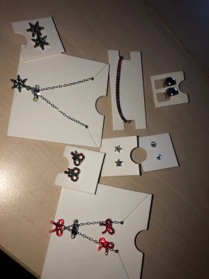 Mix av örhängen, ring och armband - Säljer ett paket med flera smycken: örhängen i form av snöflingor, rosetter, stjärnor, pärlor och julmotiv i rött, grönt och silver. Ett rött glittrigt armband och en guldfärgad ring med stjärndetalj ingår också. Perfekt för dig som gillar att variera din stil med olika former och färger. Kom med prisförslag:) 