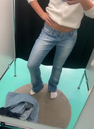 Just Cavalli bootcut jeans - Säljer ett par ljusblå jeans från Just Cavalli med bootcut passform och låg midja. Jeansen har gröna strasstenar på bakfickan som ger en unik vibe. Klassisk femficksmodell med guldfärgade detaljer och en liten slitning vid top-biten av jeansen men som ej påverkar användningen av jeansen. Perfekt för dig som gillar statement-plagg. Köpt på en second hand butik för 1400kr