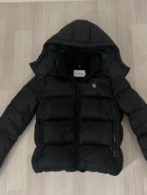 Svart pufferjacka från Calvin Klein Jeans - jätte fin bekväm jacka som knappt är använd. den har inga synliga defekter på och ser ut att va precis som ny och perfekt nu inför vinterhalvåret.  pris kan diskuteras, orginalpris ca 2700kr💗💗