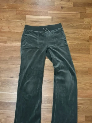 Ljusgrön mjukisbyxor från Juicy Couture - Snygga ljusgröna mjukisbyxor från Juicy Couture med broderad logga på fickan och bred resår med snörning i midjan. Byxorna har raka ben och är gjorda i mjuk sammet som känns riktigt skön mot huden. Perfekta för chill eller häng med kompisar.