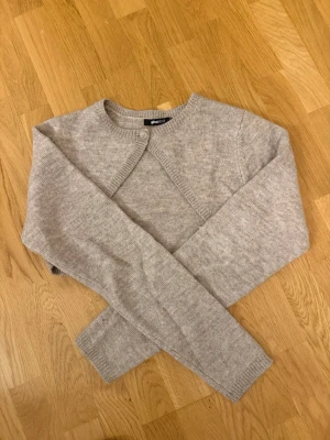 Beige croppad kofta från Gina Tricot - Säljer en beige croppad kofta från Gina Tricot i storlek M. Koftan har lång ärm, rund halsringning och en knapp framtill. Stickad i mjukt material som passar perfekt till lager-på-lager. Enkel och stilren design som är lätt att matcha.