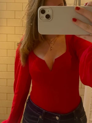 Röd body med volangärmar och urringning - bodyn är köpt från nelly och är endast använd en gång, den är i storlek S men passar både xs och M. Nypris ca 300.