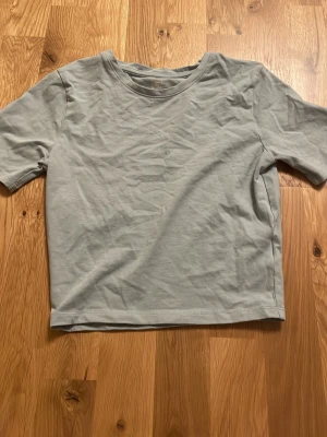 Ljusgrå t-shirt  - En enkel ljusgrå/blå t-shirt från 157. oanvänd 