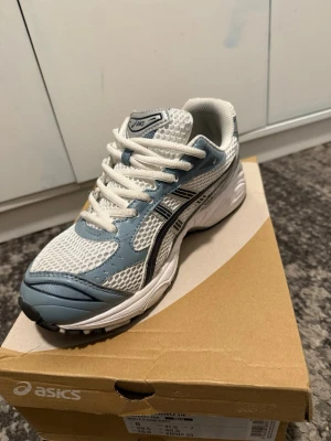 Asics sneakers i vit och ljusblå mesh - Fräscha Asics sneakers med vit mesh och ljusblå detaljer i syntet. Skorna har snörning, rund tå och platt sula. Perfekta för dig som gillar sportig stil och vill ha bekväma skor med snygg design. Liten i storleken, pris kan diskuteras.