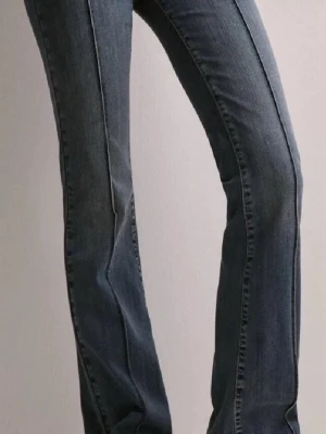 Blå bootcut jeans från Nelly - Snygga blå jeans från Nelly med bootcut-snitt och hög midja. Jeansen har klassiska fickor fram och bak, dubbla knappar i midjan och tydliga sömmar. Materialet är slitstarkt jeans med en lätt tvättad look som ger en cool vibe.