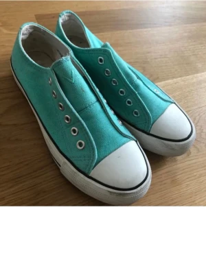 Turkosa sneakers strl 37 - Snygga turkosa sneakers med klassisk vit gummitå och vit sula med svarta detaljer. Skorna har metallöglor för snörning men saknar skosnören. Ovandelen är i tyg och sulan är mönstrad för bra grepp. Perfekt för dig som gillar färg och enkel stil. Endast provade ute en gång fri frakt 