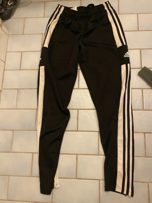 Adidas byxor med vita ränder  - Jag säljer Adidasbyxor med vita ränder och adidas loggan i vänster ben med skönt tyg oklart om det är bomull kan användas när du ska göra nån sportig sak 