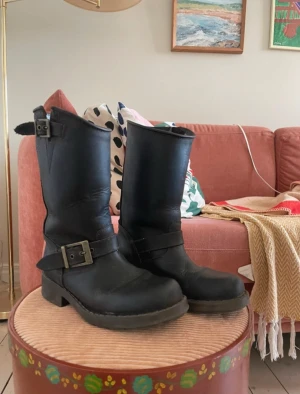 Johnny Bulls Bikerboots - Johnny Bulls Bikerboots i rejält slitstarkt läder och tålig gummisula. Strl 35. En söm har lossnat på flärpen till ena spännet, inget som påverkar funktionen dock. Snyggt slitna!