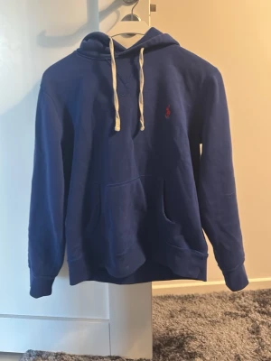 Polo Ralph Lauren hoodie - En snygg hoodie ifrån Ralph Lauren. Skicket är ganska bra skulle säga 7/10 eftersom snörerna är lite kurrvade men det går säkert att lösa på något sätt. Den är i storlek S men skulle säga att den passar XS bäst, men passar även S. Hör av er vid funderingar! 