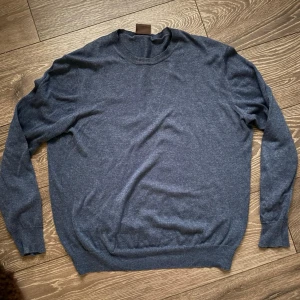 Mörkblå tröja från Oscar Jacobson - Klassisk mörkblå tröja från Oscar Jacobson i mjukt material. Tröjan har rund halsringning, långa ärmar och ribbade muddar vid ärmslut och nederkant. Perfekt för dig som gillar stilrena och tidlösa plagg. Fri frakt