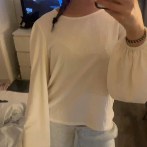 Vit blus med puffärm - Säljer en vit blus med lång puffärm och lätt texturerat tyg. Blusen har en avslappnad passform och rund halsringning, perfekt för dig som gillar stilrena och enkla plagg med en twist. Materialet känns mjukt och har en snygg struktur.