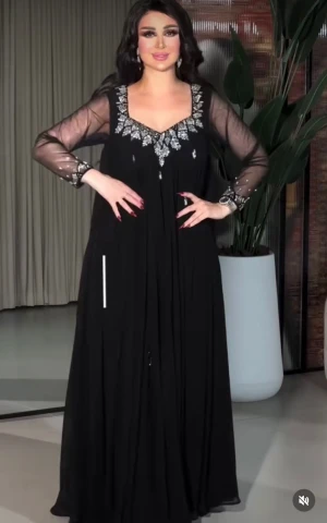 Svart långklänning med silverdetaljer - Elegant svart långklänning med transparenta långärmar och vacker silverbroderad dekor vid ringningen. Klänningen har en lös passform och är tillverkad i ett lätt, flödande material som ger en lyxig känsla.