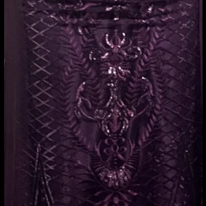 Lång lila paljettklänning med tyll - Magisk långklänning i djup lila med glittriga paljetter och broderade detaljer. Klänningen har halvtransparent tyll som sveper längs golvet och en snygg dragkedja i ryggen. Trekvartsärm och figurnära passform upptill, perfekt för bal eller fest.