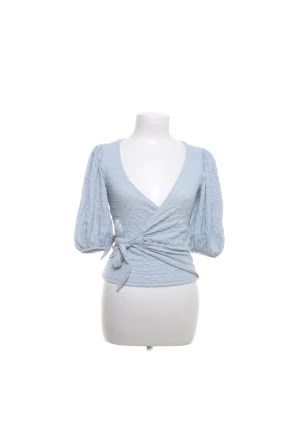 MONKI Ljusblå omlottopp med puffärm - Supersöt ljusblå omlottopp med v-ringning och knyt i midjan. Toppen har trekvarts puffärmar och en lätt strukturerad yta 🫰🤗 