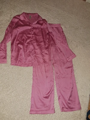 Rosa pyjamasbyxor från Lindex, 146/152 - Säljer ett par sköna silkes pyjamasbyxor från Lindex i storlek 146/152. Byxorna är tillverkade av återvunnen polyester, har elastisk midja med snörning och en relaxed passform. Perfekt för chillkvällar hemma.