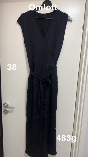Svart jumpsuit från Lindex - Svart jumpsuit från Lindex i lång modell med knytband i midjan. Jumpsuiten har en v-ringad hals och är ärmlös, vilket ger en stilren och enkel look. Perfekt för dig som gillar minimalistisk stil och vill ha något som känns både bekvämt och snyggt.🌸 Fint använt skick. Storlek 38