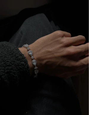 Glittrigt armband med droppformade stenar - Ett riktigt snyggt armband i silverfärg med stora droppformade glittriga stenar och små runda stenar mellan varje. Perfekt för dig som vill sticka ut och addera lite extra bling till din stil. Låset är diskret och smidigt, och hela armbandet har en lyxig känsla.