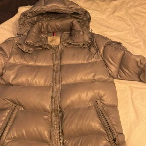 Grå dunjacka från Moncler - Säljer en snygg grå dunjacka från Moncler med huva och dragkedja. Jackan har en quiltad design och praktiska fickor med dragkedjor. Perfekt för kyliga dagar! Tillkommer också dustbags kvitto är tyvär borttappat. Kan gå med på seriösa byten 