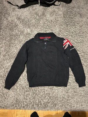 Henri Lloyd halfzip - Marinblå stickad halfzip från Henri Lloyd. Skicket är helt okej, den har lite slitage i slutet av ärmarna. Men annars bra skick.