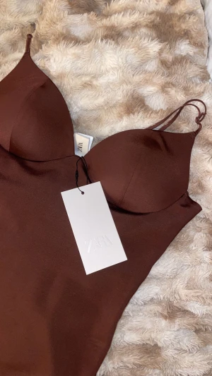 Brun satin korsettopp från Zara - Supersnygg brun korsettopp från Zara i glansigt satinmaterial. Storlek M, men passar S också då kupan är liten och materialet stretchigt. 