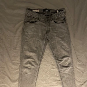 Replay grå jeans Willbi strl 30 - Snygga grå jeans från Replay, modell Willbi. De har klassisk femficksdesign, raka ben och coola detaljer på bakfickorna. Jeansen är tillverkade i mjukt denim och har en modern, slim passform som sitter riktigt bra.