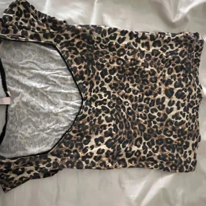 Leopardmönstrad topp - Snygg top med leopardmönster i beige, brunt och svart. Djup v-ringning och korta ärmar ger en trendig look. Perfekt för dig som vill sticka ut och älskar djurmönster. Knappt använd.