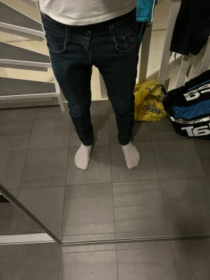 Replay Anbass mörkblå jeans, W30/L30 - Säljer ett par snygga Replay Anbass jeans i mörkblå tvätt. Modellen på jeansen är anbass. Modellen på bilden är 178 cm. Jeansen är tillverkade i stretchig bomull för extra komfort och sitter riktigt bra på benen.