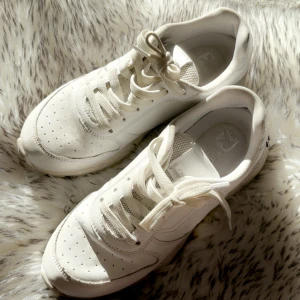 Vita sneakers från Revolution, använda bara 3 gånger👟✨🤍 - Vita sneakers från Revolution med platt sula. storlek 36. Skorna har snygga detaljer i vitt och har klassisk snörning. Tillverkade i syntetmaterial med en stilren look som passar till jeans eller shorts. Perfekta för dig som gillar clean och enkel stil.
