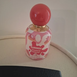 Tubbees Strawberry Cheesecake Parfym 50 ml - Färgglad parfym med lekfull design inspirerad av jordgubbscheesecake. Perfekt för dig som gillar söta och unika dofter. Eau de Parfum i sprayflaska, passar dig som vill sticka ut med din stil. Enbart testad.