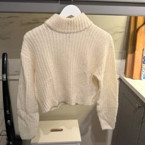 Vit stickad polotröja - Mysig vit stickad polotröja med grov ribbad krage och lång ärm som är från H&M. Tröjan har en något croppad passform och är perfekt för kyliga dagar.