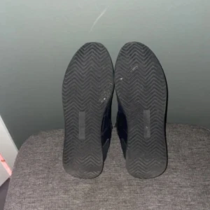 Svarta sneakers från Philippe Model - Säljer ett par svarta sneakers från Philippe Model med vita detaljer och snörning. Skorna har en klassisk sportig design med rund tå och platt sula. Materialmix av mocka och syntet, perfekt för dig som gillar stilrena och bekväma sneakers.