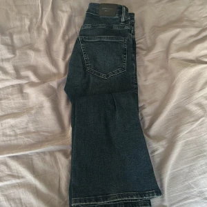 Mörkblå Perfect Jeans bootcut - Snygga mörkblå jeans från Perfect Jeans med klassisk femficksdesign och bootcut-ben. Jeansen har kopparfärgade nitar, normalhög midja och är tillverkade i stretchigt denim för skön passform. Perfekta för dig som gillar en tidlös look med lite extra vidd nedtill.