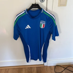 Italien blå fotbollströja Adidas - Italiens Hemmatröja 2025. Köpt ifrån Unisport. Storlek S