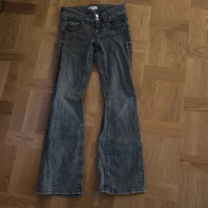 Grå bootcut jeans från Gina Tricot - Snygga grå jeans från Gina Tricot i storlek 152. Modellen har bootcut-ben, klassiska fem fickor och coola detaljer med svarta sömmar och knappstängning. Jeansen är i ett mjukt denimtyg och har en lite tvättad look. Inga hål eller fläckar.