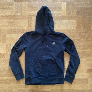 J.Lindeberg hoodie - Säljer denna riktigt snygga svarta hoodien från J.Lindeberg! Mycket bra skick överlag förutom hålet som syns i bilden, storlek S, 58 cm lång och 45 cm bred under armhålorna, hör gärna av dig vid frågor!