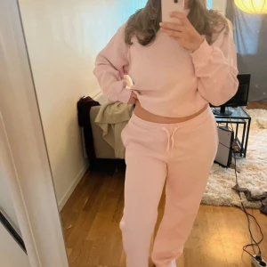 Ljusrosa set med byxor och tröja - Säljer ett  ljusrosa set med byxor och tröja. Snörning i midjan. Väldigt skönt och mysigt! Tyvärr inte riktigt min färg därav knappt använda. Byxorna är lite smutsiga nedtill men går lätt bort i tvätten! Ett yttepytte hål i ena fickan på byxorna men inget som syns eller påverkar funktionen. Hålet sitter på sidan av fickan dvs inte i fickan. 