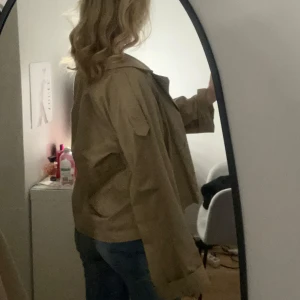 Trenchcoat - Snygg brun/beige trenchcoat från gina tricot! Kommer tyvärr ej till användning då den är för stor på mig som vanligtvis har strl S