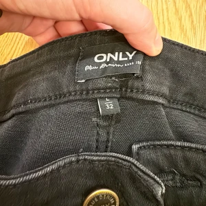 Svarta jeans från ONLY, stl L/32 - Svarta jeans från ONLY Denim med klassisk femficksdesign och knappstängning. Jeansen har en rak passform och är tillverkade i ett mjukt bomullsmaterial med lite stretch för extra komfort. Perfekta för en avslappnad och stilren look. 