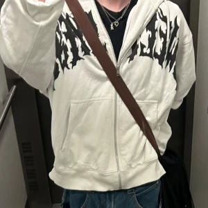 Vit hoodie från Junkyard med tryck L - Vit hoodie från Junkyard i storlek L med svart grafiskt tryck över bröstet. Tvättad en del och därav lite skrynklig(går såklart att stryka etc)  men annars i bra kondition. Frågor? Fråga på!