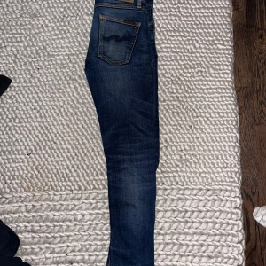 Nudie Jeans - Säljer ett par blå skinny jeans från Nudie Jeans i storlek 27/30. Dom är i bra skicka endast en slitning vid fotleden! Kan gå ner i pris vid snabb affär🙌