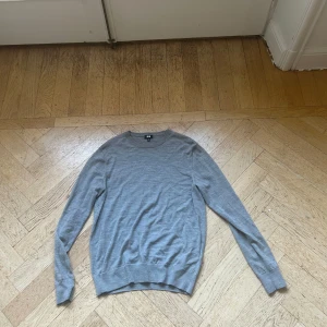 Grå merinoulltröja från Uniqlo - Säljer en stilren grå tröja från Uniqlo i mjuk merinoull. Tröjan har rund halsringning, lång ärm och en clean, klassisk look som funkar till allt. Perfekt för lager-på-lager och enkel att matcha med jeans eller chinos.