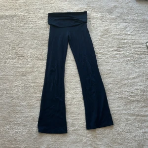 Mörkblå yoga pants från Gina Tricot - Snygga mörkblå yoga pants från Gina Tricot med stretchigt bomullsmaterial. Byxorna har en bred linning som kan vikas ner och en klassisk utsvängd passform nertill. Perfekta för en trendig och bekväm stil. Storlek 146-152
