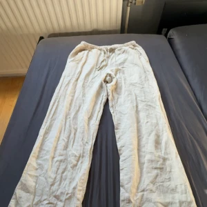 Beiga linnebyxor - Säljer ett par beiga linnebyxor från Gina Tricot med avslappnad passform och resår i midjan. Byxorna har snörning framtill och raka ben, perfekta för en chill och luftig stil. Materialet är linne som ger en skön känsla och snyggt fall.