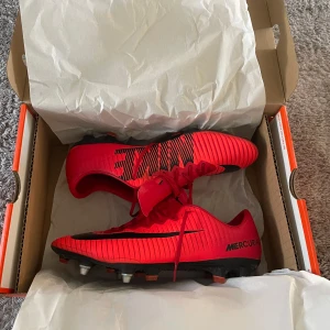Röda Nike Mercurial vapor XI - Säljer ett par röda Nike Mercurial fotbollsskor med svarta detaljer och snörning. Skorna har en smal och sportig form, mönstrad ovandel och dobbar för bästa grepp på planen. Perfekta för dig som vill sticka ut på fotbollsplanen. Kom privat för fler bilder.                                                        Se bild 4