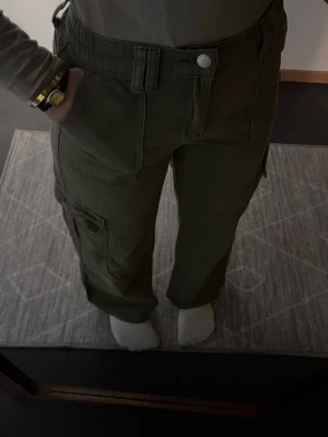 Olivgröna cargobyxor från SHEIN - Säljer ett par olivgröna cargobyxor från SHEIN i storlek S. Byxorna har flera praktiska fickor på sidorna, raka ben och hög midja. Tillverkade i bomullsmix som känns sköna och slitstarka. Perfekta för en avslappnad och trendig look.