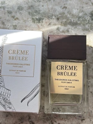 Crème Brûlée parfym 50ml - En lyxig parfym med gourmanddoft, inspirerad av crème brûlée. Flaskan är rektangulär i genomskinligt glas med en elegant träfärgad etikett och ett mörkt trälock. Innehåller 50 ml extrait de parfum.