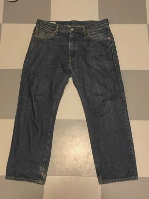Levi's 555 Raka Jeans blåa - Klassiska blå jeans från Levi's med rak passform och fem fickor. Jeansen har en mörk tvätt, synliga sömmar och den ikoniska läderpatchen bak i midjan. Tillverkade i slitstarkt denim med Levi's röda etikett på bakfickan.