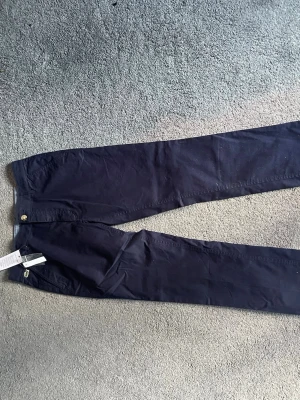 Mörkblå chinos från Psycho Bunny - Snygga mörkblå chinos från Psycho Bunny med klassisk rak passform. Byxorna har diskret logga med kaninbrodyr vid fickan och levereras med extra knapp. Tillverkade i mjukt bomullstyg för en bekväm känsla.