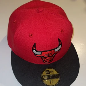 Chicago Bulls röd och svart keps - Säljer en snygg röd och svart 59FIFTY keps från New Era med Chicago Bulls-logga broderad framtill. Klassisk flat brim och broderade ventilationshål. Kepsen är i bomull och har officiella NBA-märken på insidan. Perfekt för dig som gillar streetwear och sport.Använd cirka 1 gång tror jag och priset är diskuterbart! Perfekt till dig som vill ha en uppgradering till din outfit inför våren, sommaren och generellt hela året runt ❤️🌻
