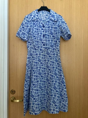 vintage style klänning - fin mönstrad klänning i vintage stil från okänt märke. blåa knappar fram och dragkedja i sidan. luftig och sval, perfekt för varma sommarkvällar. har en liten röd missfärgning fram som knappt syns.